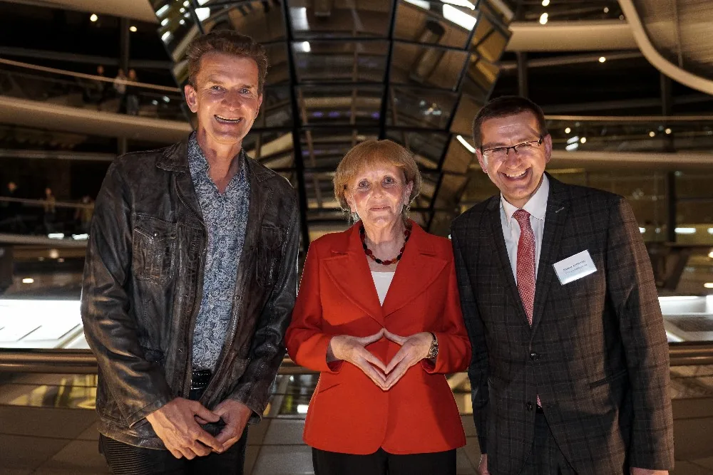 Drei Teilnehmende bei einer Veranstaltung in einer Ausstellungshalle