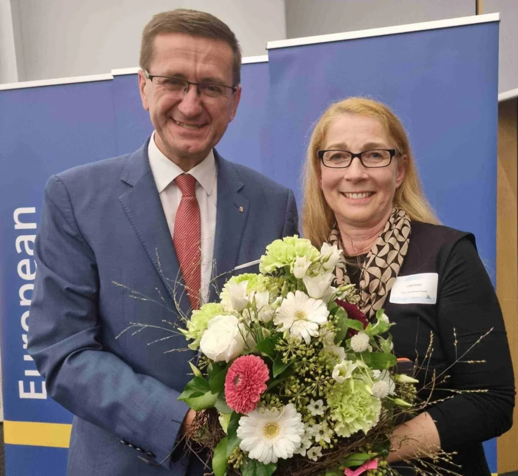 Zwei Personen mit Blumenstrauß vor einer EWA-Bannerwand