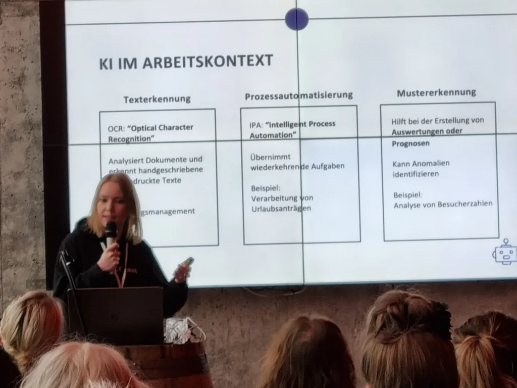 Referentin vor einer Präsentationsfolie zum Thema KI im Arbeitskontext