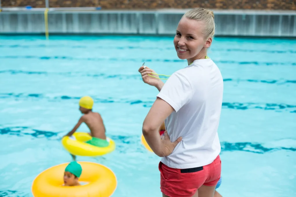 Bademeisterin am Beckenrand vor schwimmenden Kindern