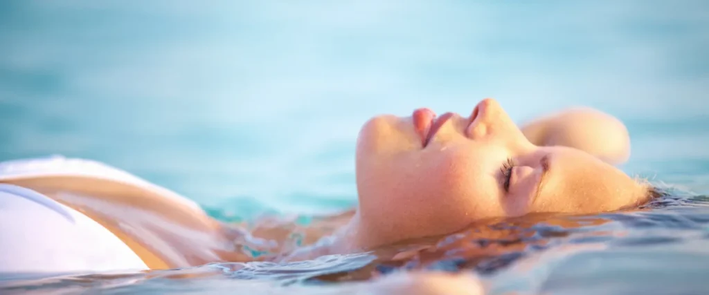 Frau entspannt im Wasser eines Schwimmbads