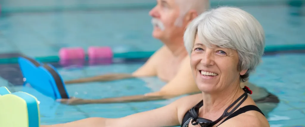 Seniorin trainiert mit Schwimmbrett im Hallenbad